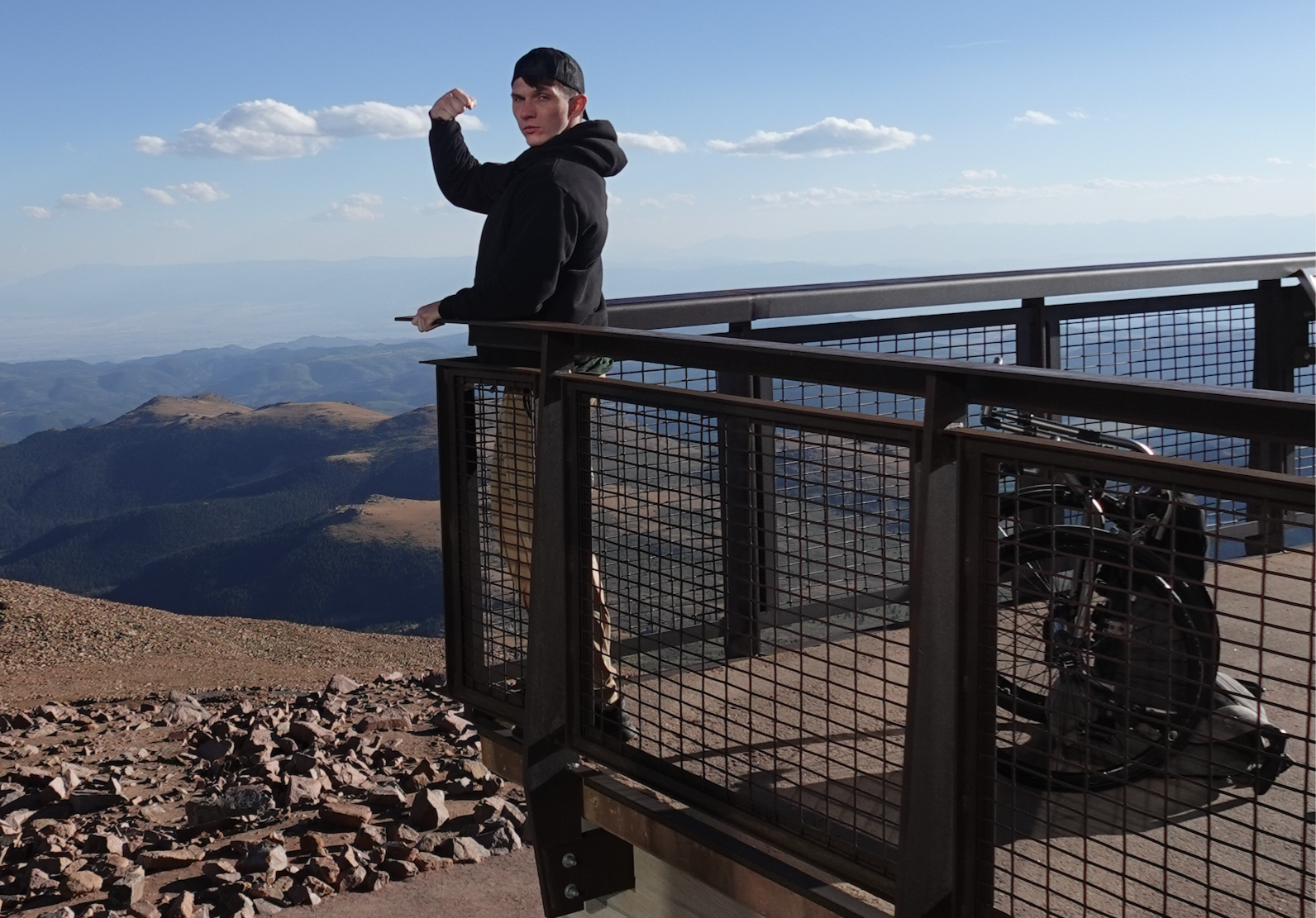 Sam Primeaux standing on Pikes Peak mountain top with scenic view.